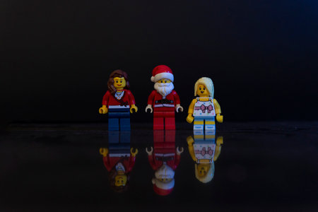 Bauru, Brazil. June 1, 2022: Santa Claus minifigure standing near a mom and her daughter on Christmas night. Birthday of Jesus Christ celebrated by Christians. Text area.のeditorial素材