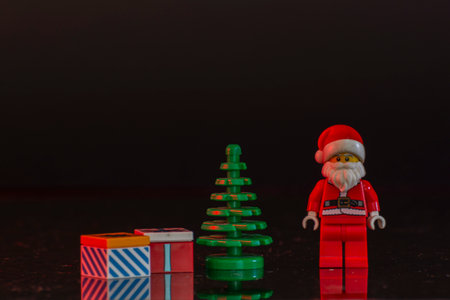 Bauru, Brazil. June 1, 2022: Lego Santa Claus minifigure standing near the Christmas tree, tand gifts on Christmas night. Birthday of Jesus Christ celebrated by Christians. Text area.のeditorial素材