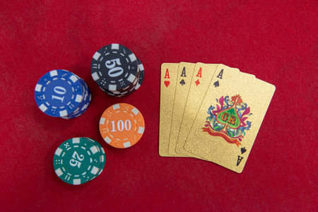 Four of aces near stacks of chips on a red felt table. Poker game is one of the most popular card games in the world and played a lot in casinos. cards on the tableの写真素材