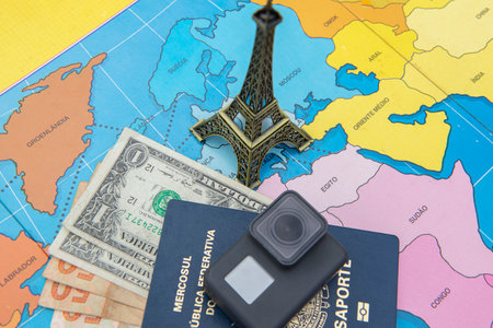 Bauru, Brazil - 11 Jan, 2023: Passport, with several banknotes inside it, camera and miniature of the Eifel Tower on a world map, international travel, planning and tourism travel conceptのeditorial素材