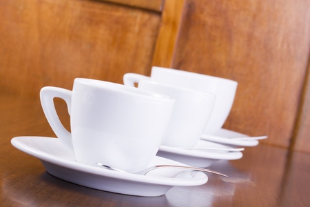 Three coffee cups in a row, served on wooden tableの写真素材