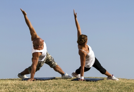 Couple doing yoga in nature  Beautiful blue skies in bacground の写真素材
