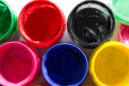Jars with colored gouache paint on white background
