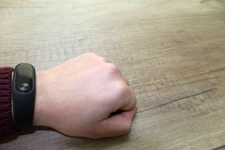 Hand with a fitness clock on a wooden table close-upの写真素材