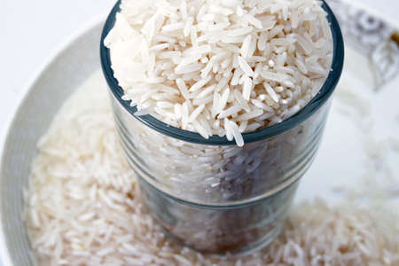 Uncooked rice in a glass on isolated whiteの写真素材