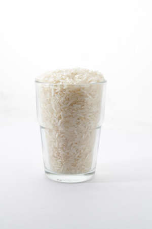 Uncooked rice in a glass on isolated whiteの写真素材