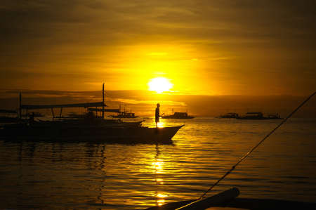 people fisherman on the boat is worth looking into the distance at sunrise on the background of the sea Philippinesの写真素材