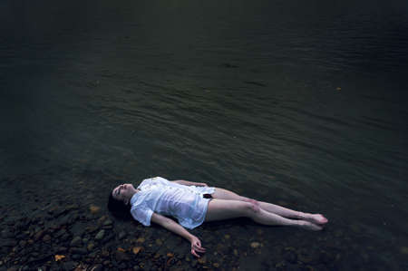 Floating girl lying on the rock of dark river . Ophelia conceptualの写真素材
