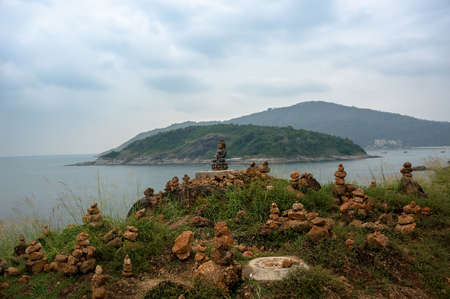 little Buddha statue on the island near the sea. An altar for meditation, worship and prayer. The stone rests on stone pyramidの写真素材