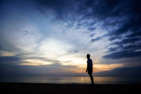 a lone man stands on the beach and looking into the distance flying towards him on the plane on the...