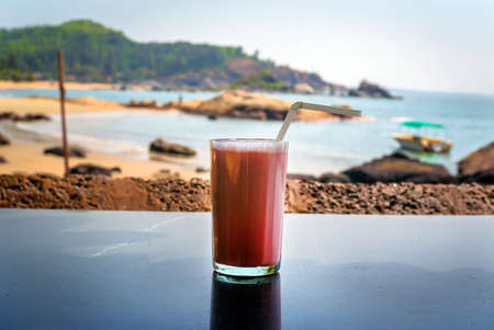 Strawberry cocktail with a straw in a glass stands on the table on background of sea. breakfastの写真素材