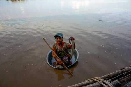 the poor child with snake floats in a basin of dirty Tonle SAP lake in Cambodia. 22 may 2016のeditorial素材
