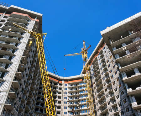 Two yellow crane building a multistory residential building blocks.