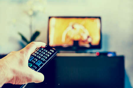 Men with the remote control front of the television. Photo toning in a retro style.の写真素材