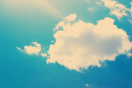 clouds in vintage style. sky with clouds Stylized under the old photographs. The sun is bright shining blue through a small cloud.の写真素材