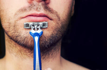 Time for new razor. Closeup of a razor on his chin stubbly.の写真素材