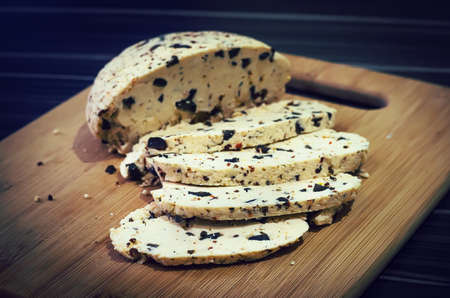 Delicious healthy homemade cheese on a wooden table, cut into piecesの写真素材