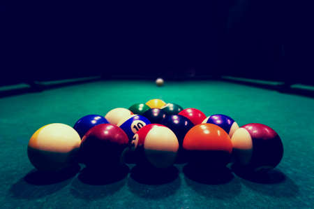 Billards pool game. Color balls in triangle, aiming at cue ball. black night background