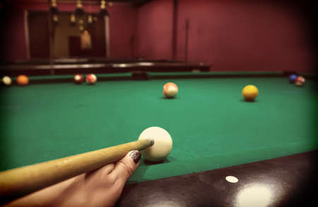 Hand of a Caucasian girl playing billiards pool game.