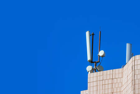 Mobile antenna in the roof of a building, against blue skyの写真素材