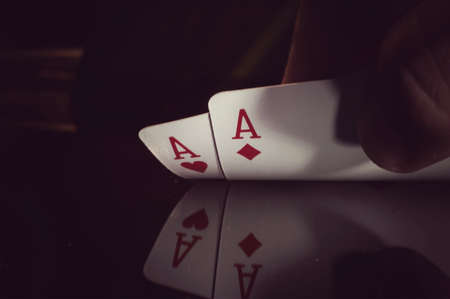 human hand holding two aces on a black backgroundの写真素材