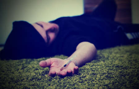 Close-up on the floor of the syringe with the drug. In the background, a young drug addictの写真素材