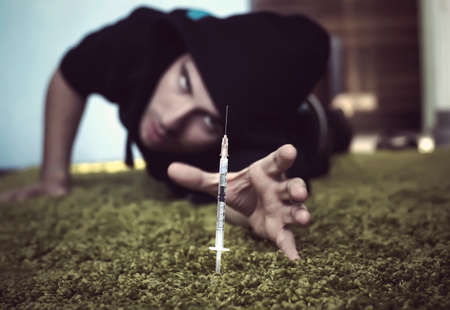 a crazed drug addict reaches for another dose of the drug in the syringe.の写真素材