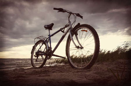 Bicycle near lake during sunset.Vintage bike near the lake in the evening, warm sunset view. Toned retro photo.の写真素材
