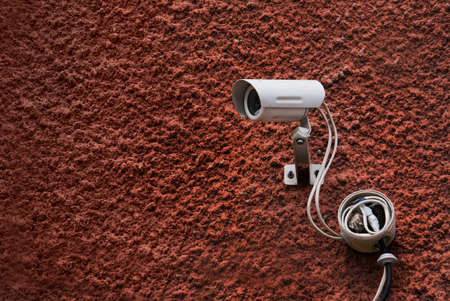CCTV security camera and dark red wall with white wires. Security camera