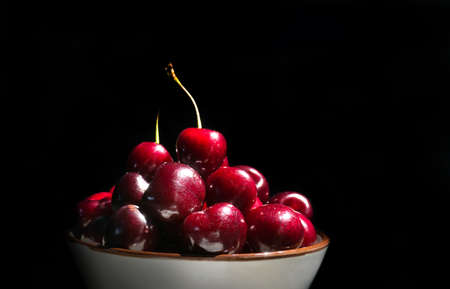 cherries on a black background. ripe cherries in the plate