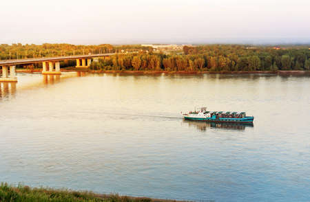Scenic evening view of the river. The ship floats on the river under the bridge.の写真素材