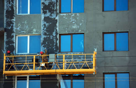 orange construction Elevator with the workers against the wall of a building under construction. Rachie make the facade of the buildingの写真素材