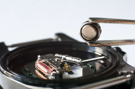 Replace the battery in a wristwatch. Close-up Of Tweezers Placing Battery On Wrist Watchの写真素材