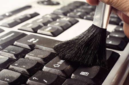 cleaning keyboard with brush. removing dust from a dirty keyboard on the computeの写真素材