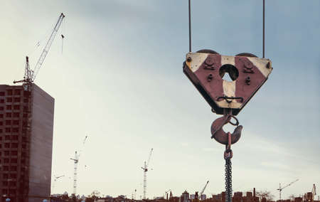 Big hook from the tower crane closeup on the background of a great line in an industrial developing city. Lots of tower cranes build different houses.の写真素材