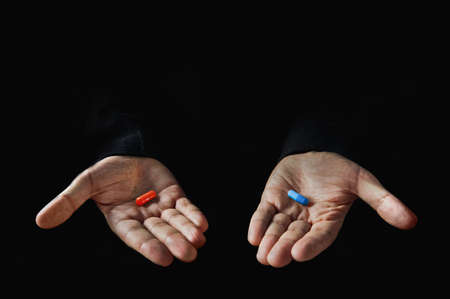 Red and blue pills on hand isolated on black backgroundの写真素材