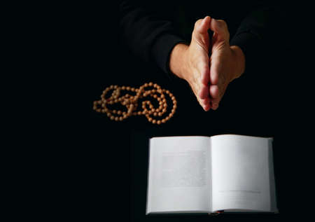 Male hand folded in prayer rosary beads closeup and koran on background.の写真素材
