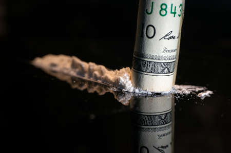 Snorting a line of cocaine. There are three lines on a glass table. snorting through a rolled bill....