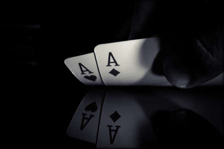 A pair of aces on a black background in hand from puckerman. Winning the game of cards. Playing cards in good combinations. black and white photo.の写真素材