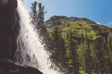 waterfall with mountains in the background. water flows through the stone.の写真素材