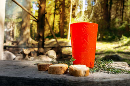 Cool cocoa in a plastic orange glass placed on a wooden table in the garden. Cold drink in nature blurred background.の写真素材