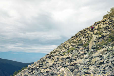 A tourist makes its way through the stone placers Man climb on mountain hillの写真素材