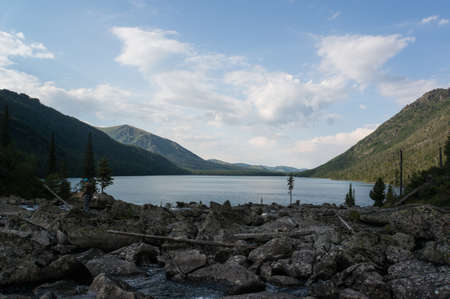 Rocks near Multinskoe lake, Altai mountains. Russia. The beautiful mountain scenery. The lake in the foreground with mountains in the background on top of which the snowの写真素材
