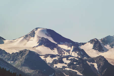Alpine landscape in dull colours. Snow capped high mountains. Tinted instagram photosの写真素材