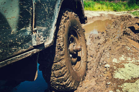 truck on a bad road. The wheel of the SUV in the mud in the foreground.の写真素材