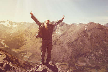 Hiker standing on top of a mountain with raised hands and enjoying sunrise. Tourists with raised arms in the background of a beautiful mountain landscape with a lake and a riverの写真素材
