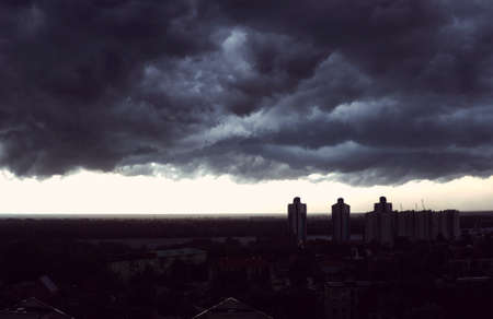 Storm clouds cover the city. Storm front over tall buildings and amid the rivers and forestsの写真素材