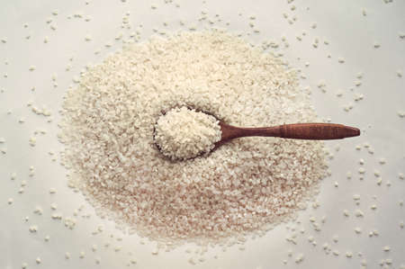 Uncooked rice in wooden spoon over white background. Close up, top view, high resolution product. Long-grain rice. The food is poor and starvingの写真素材