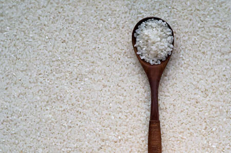Raw white rice in spoon on wooden backgroundの写真素材