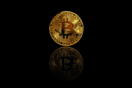 Golden bitcoin on black background with a reflective surface. Bitcoin cryptocurrency close-upの写真素材